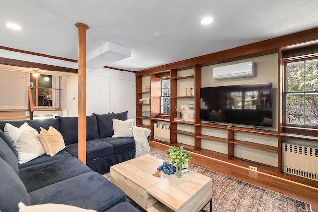 living area with ornamental molding, an AC wall unit, radiator heating unit, and wood finished floors