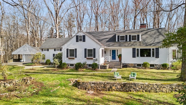 view of front facade with an outbuilding, a front lawn, a detached garage, a chimney, and a shingled roof
