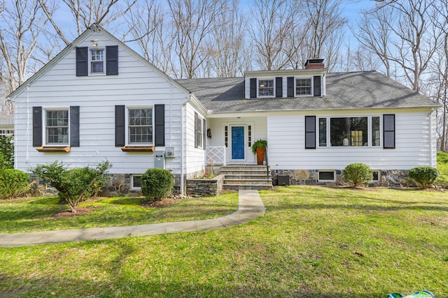 view of front of home with a front lawn, roof with shingles, and a chimney