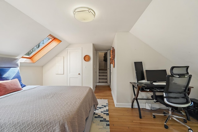 bedroom featuring baseboards, wood finished floors, and vaulted ceiling with skylight