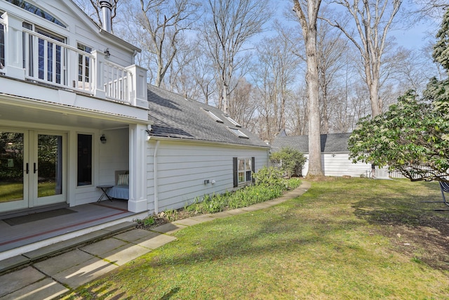 view of yard with french doors, an outdoor structure, and a balcony