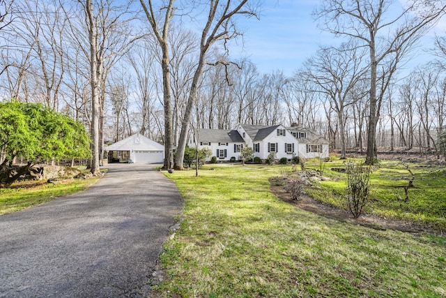 view of front of house with an outdoor structure, a chimney, a front yard, and a garage
