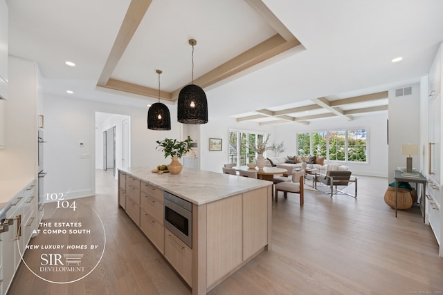 102 Compo Rd S, Westport, CT 06880 - kitchen with stainless steel microwave, visible vents, light wood finished floors, light brown cabinetry, and a kitchen island