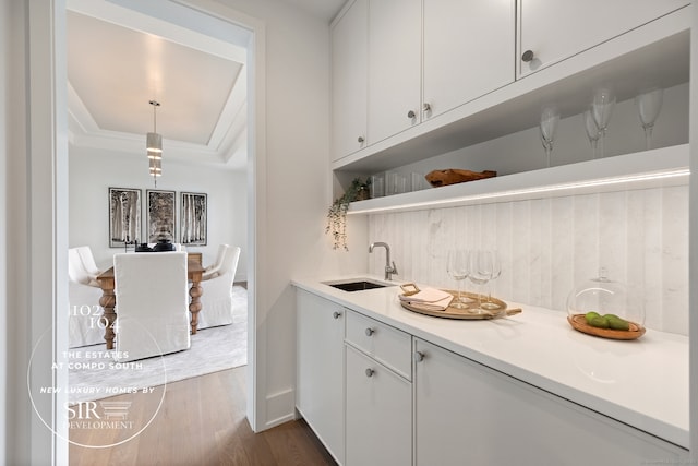 102 Compo Rd S, Westport, CT 06880 - bar featuring a sink, indoor wet bar, dark wood-style floors, a tray ceiling, and hanging light fixtures