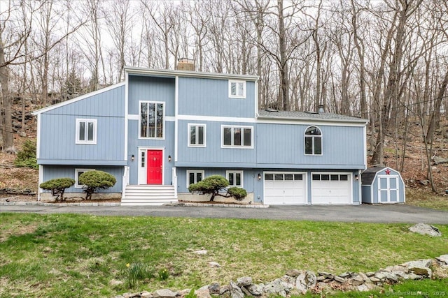 594 Barrack Hill Rd, Ridgefield, CT 06877 - view of front facade with a storage shed, a chimney, asphalt driveway, an attached garage, and a front yard