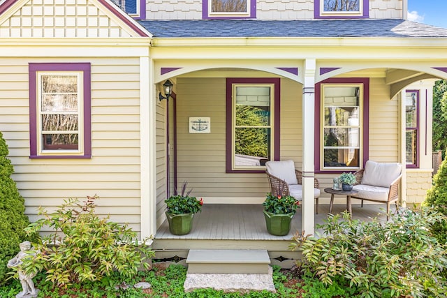 entrance to property featuring a shingled roof and covered porch