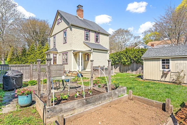 rear view of house featuring fence, a vegetable garden, a chimney, an outdoor structure, and a yard