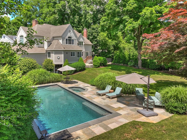 pool featuring a lawn, an in ground hot tub, and a patio area