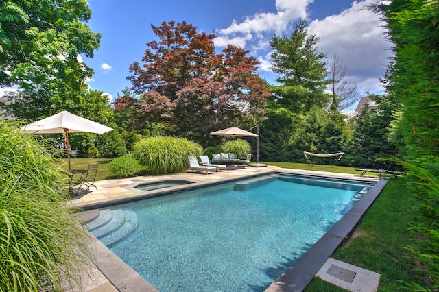 pool featuring a patio, an in ground hot tub, and a yard