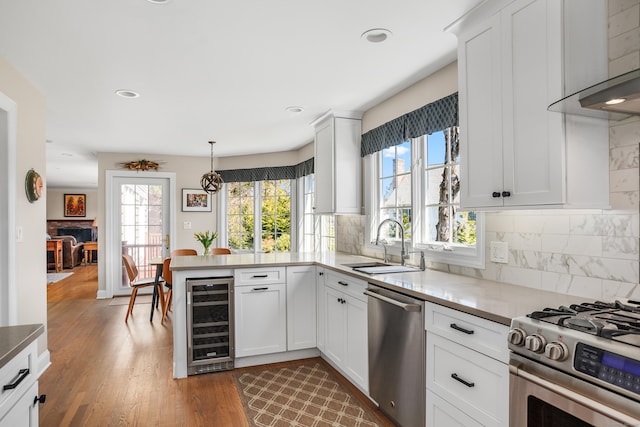 kitchen with wine cooler, a peninsula, a sink, backsplash, and stainless steel appliances