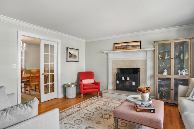living area featuring crown molding, wood finished floors, a premium fireplace, and french doors