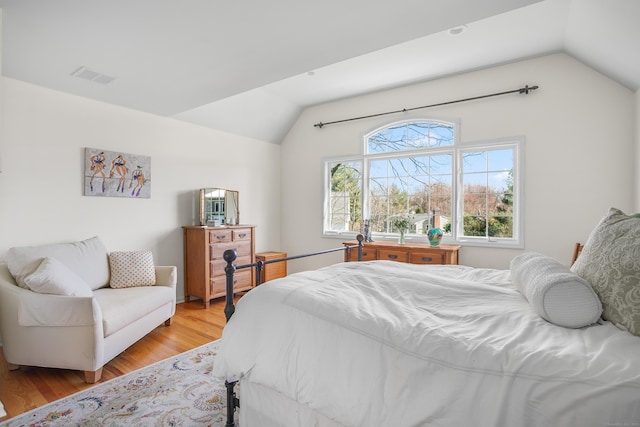 bedroom featuring visible vents, light wood finished floors, and lofted ceiling