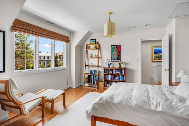 bedroom with baseboards, wood finished floors, and visible vents