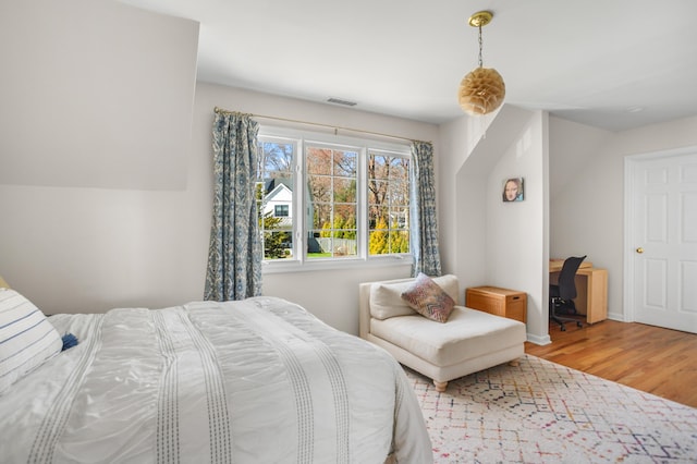 bedroom featuring baseboards, wood finished floors, and visible vents
