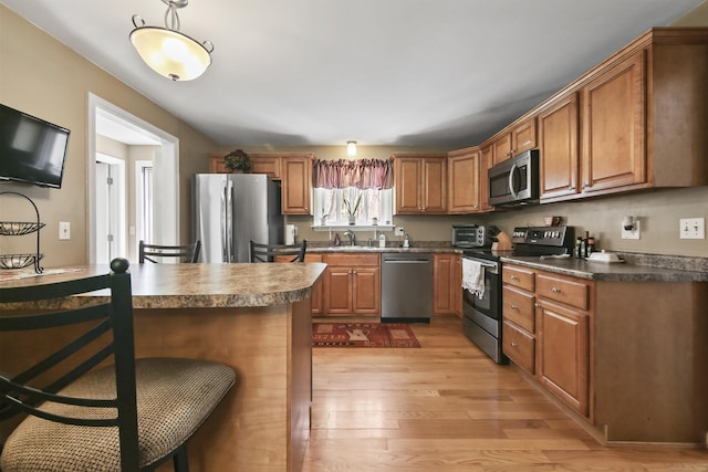 43 Attawanhood Trl, Hebron, CT 06231 - kitchen with brown cabinetry, appliances with stainless steel finishes, dark countertops, a sink, and light wood-type flooring
