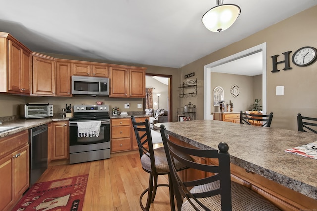 43 Attawanhood Trl, Hebron, CT 06231 - kitchen with brown cabinets, a kitchen bar, light wood-type flooring, a toaster, and appliances with stainless steel finishes
