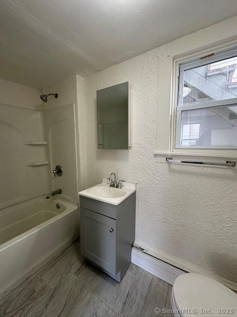 bathroom with toilet, a textured wall, vanity, and washtub / shower combination