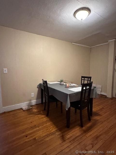 dining area with a textured ceiling, wood finished floors, and baseboards