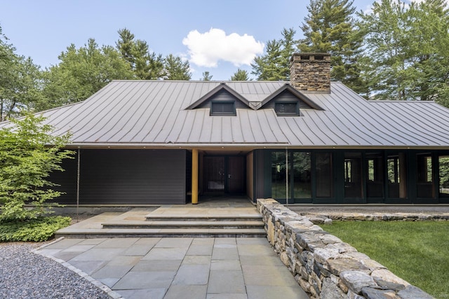 view of front of property with a chimney, a standing seam roof, and metal roof