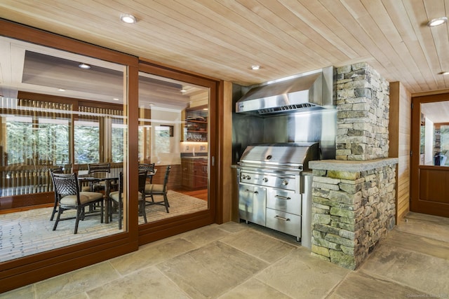 interior space featuring wall chimney range hood, stone finish flooring, and wood ceiling