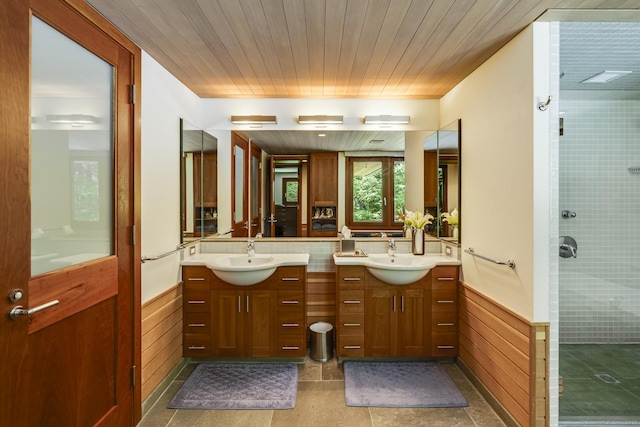 bathroom featuring wooden walls, vanity, a wainscoted wall, and a stall shower