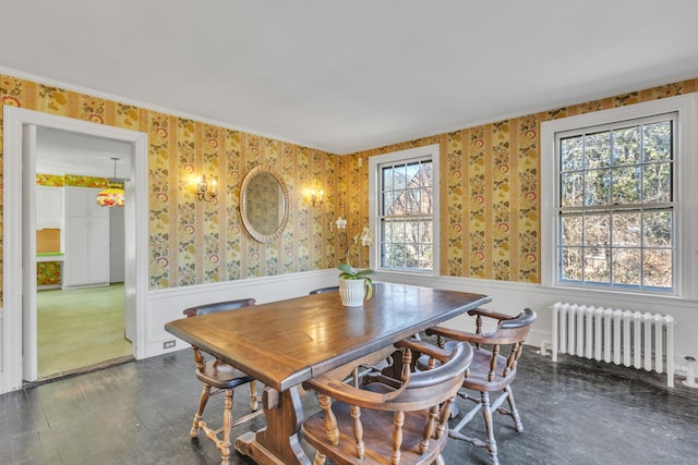 dining area featuring radiator heating unit, wallpapered walls, and wainscoting