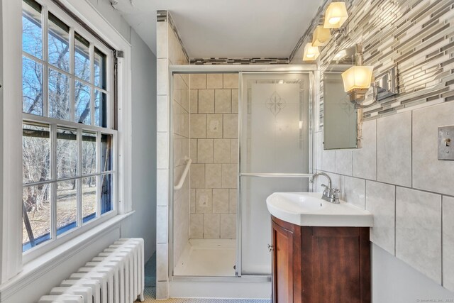 full bath with radiator, tasteful backsplash, vanity, and a stall shower