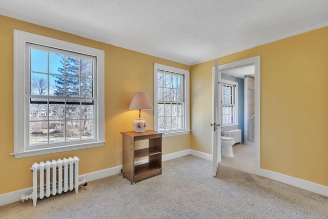 unfurnished room featuring radiator, carpet floors, radiator heating unit, and a textured ceiling
