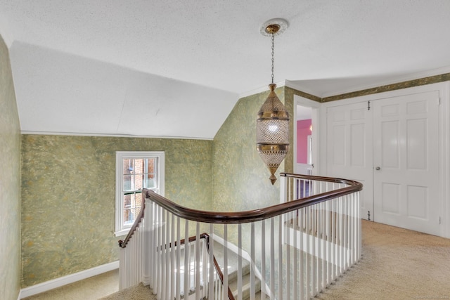 hallway with lofted ceiling, carpet flooring, an upstairs landing, and baseboards