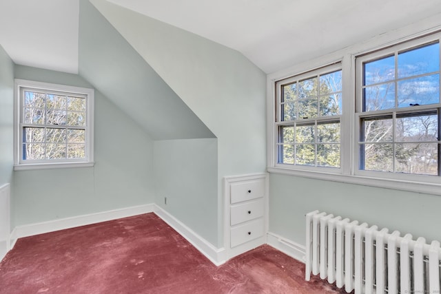 additional living space with radiator heating unit, carpet floors, lofted ceiling, and a healthy amount of sunlight