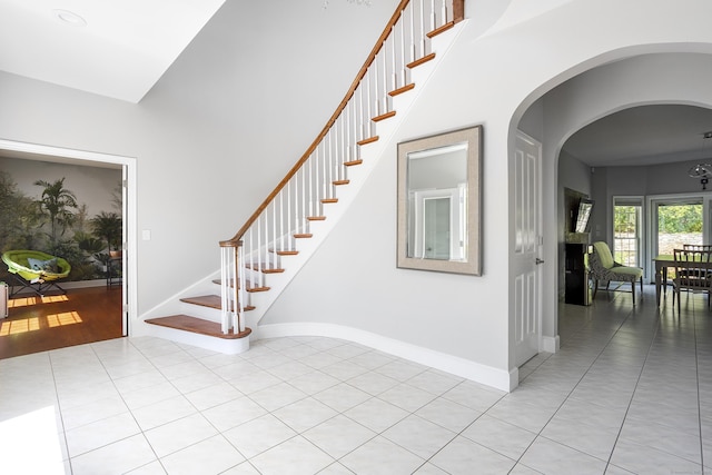 21 Centennial Dr, Danbury, CT 06811 - staircase with arched walkways, baseboards, tile patterned flooring, and a towering ceiling