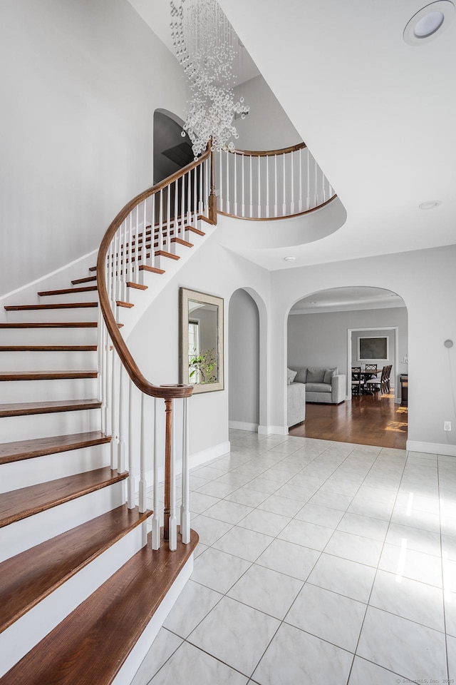 21 Centennial Dr, Danbury, CT 06811 - stairway featuring arched walkways, baseboards, a high ceiling, and tile patterned flooring