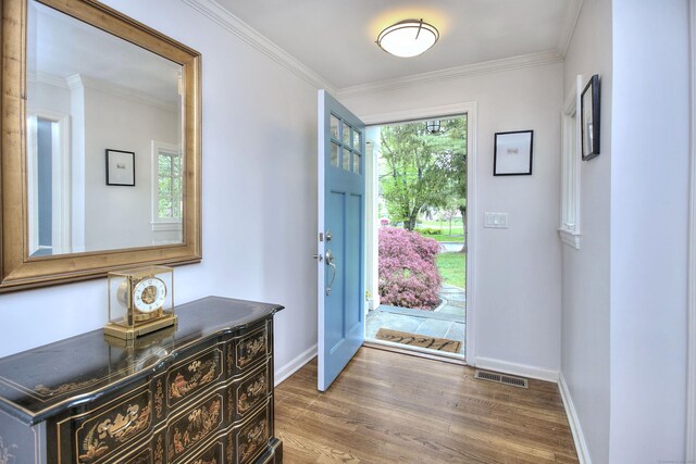 entrance foyer featuring ornamental molding, baseboards, visible vents, and wood finished floors