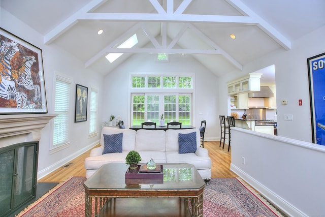 living area with light wood finished floors, recessed lighting, a fireplace with flush hearth, and beam ceiling