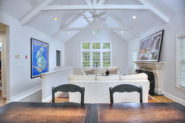 living room with beamed ceiling, a fireplace, ceiling fan, and wood finished floors