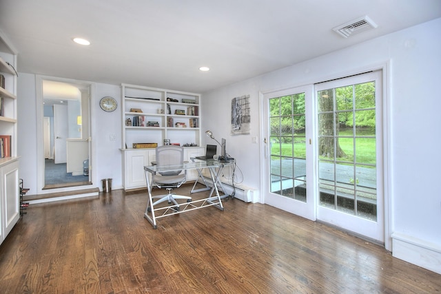 office with dark wood finished floors, visible vents, built in shelves, a baseboard radiator, and recessed lighting