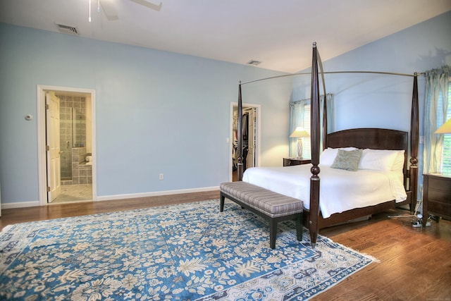 bedroom with ensuite bath, visible vents, wood finished floors, and baseboards