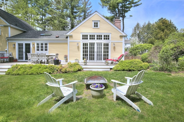 back of property featuring an outdoor fire pit, a yard, a chimney, and french doors