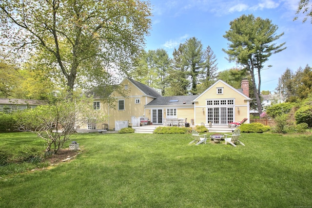 back of property featuring a lawn, a chimney, french doors, a patio area, and a fire pit