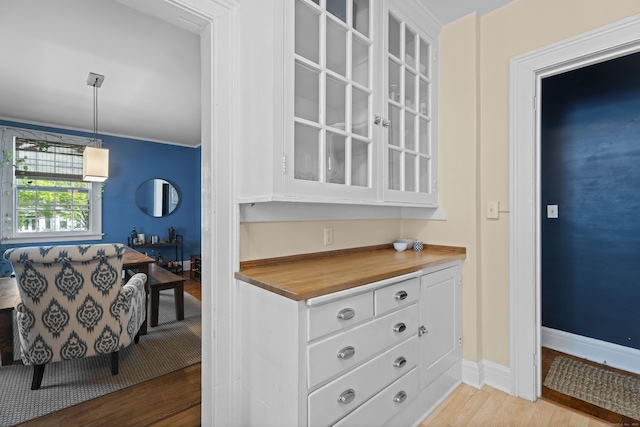 498 Whitney Ave Unit 1D, New Haven, CT 06511 - kitchen featuring light wood-style flooring, white cabinetry, wood counters, glass insert cabinets, and baseboards