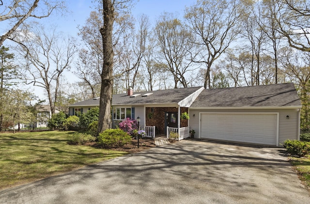 ranch-style house featuring covered porch, aphalt driveway, a chimney, a front lawn, and an attached garage