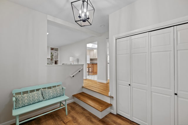 interior space featuring baseboards, a chandelier, wood finished floors, and an upstairs landing