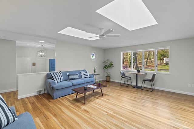 living room featuring a skylight, baseboards, wood finished floors, and visible vents