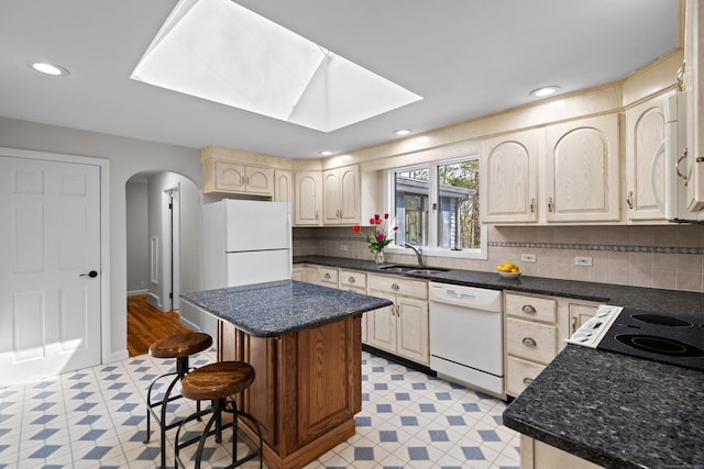 kitchen featuring white appliances, arched walkways, a sink, and light floors