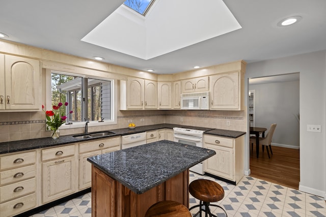 kitchen with a kitchen bar, a skylight, a sink, recessed lighting, and white appliances