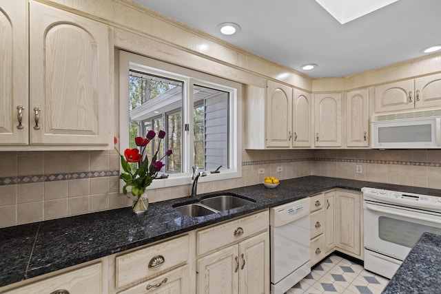 kitchen featuring white appliances, a sink, dark stone counters, and tasteful backsplash