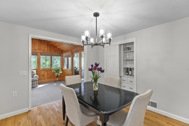 dining area with visible vents, lofted ceiling, baseboards, a chandelier, and light wood finished floors