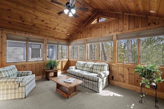 sunroom featuring wood walls, wood ceiling, a ceiling fan, and lofted ceiling