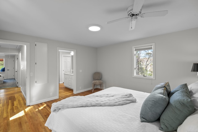 bedroom with baseboards, multiple windows, wood finished floors, and attic access