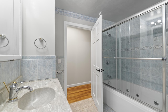 full bathroom with tile patterned flooring, enclosed tub / shower combo, a wainscoted wall, and vanity